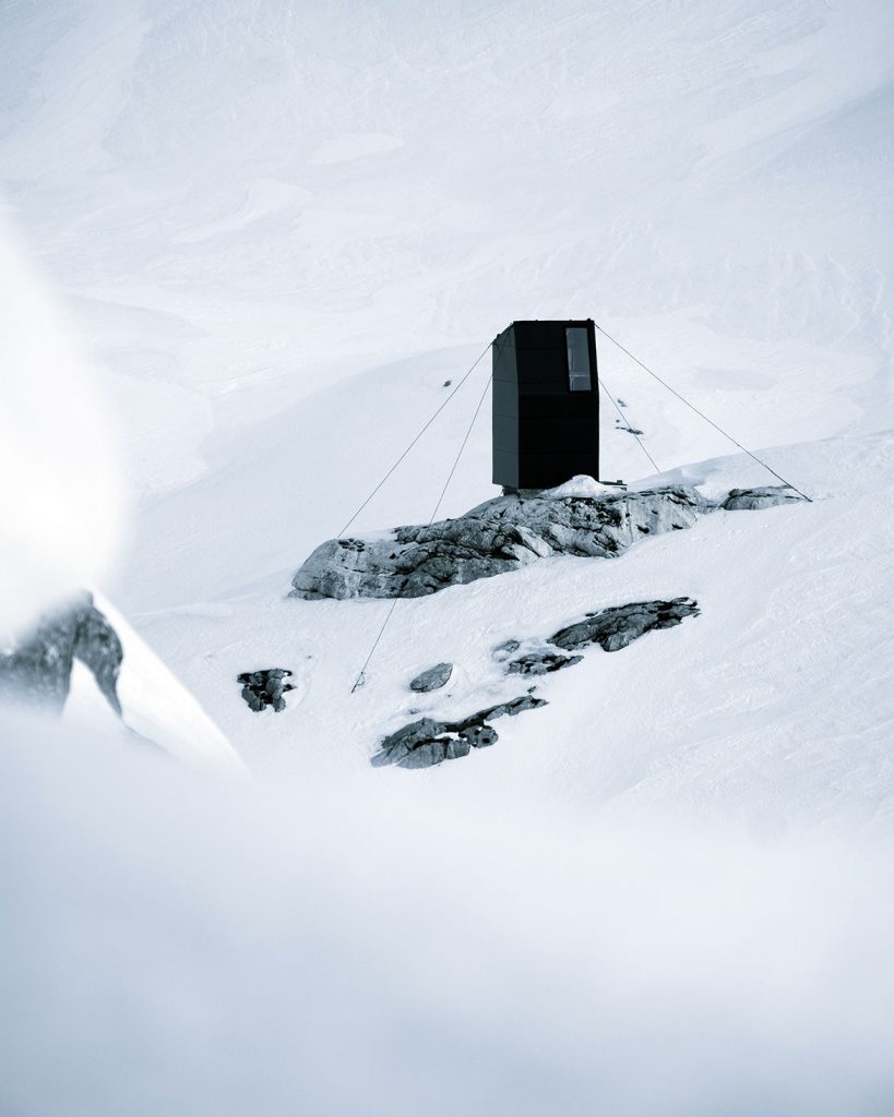 Photo showing a black box like house-like structure in a snowy alpine landscape (Kranj, Slovenia)