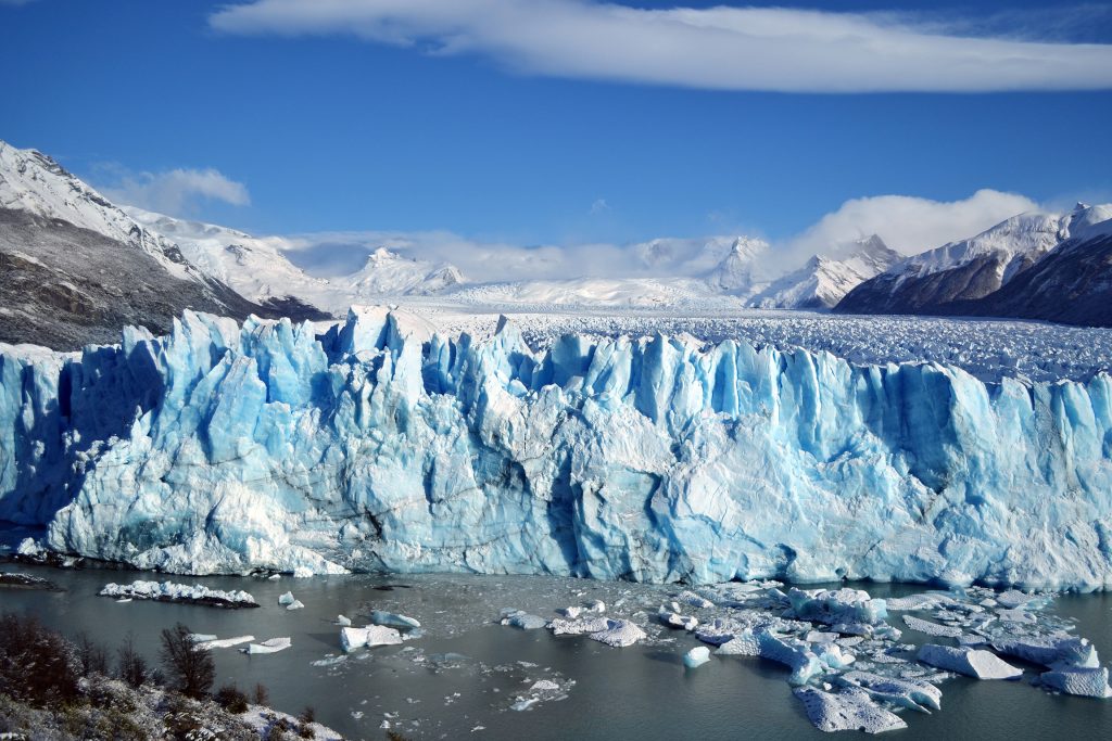 Photo of Perito Moreno Glacier, Los Glaciares National Park, Argentina in sunshine. Below the glacier edge, meltwater accumulates. 