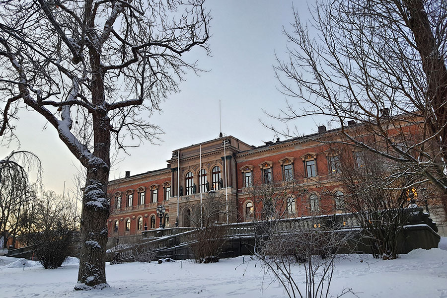 Photo of Uppsala University Main Building, a late 1800s brick building, with December snow and winter cold