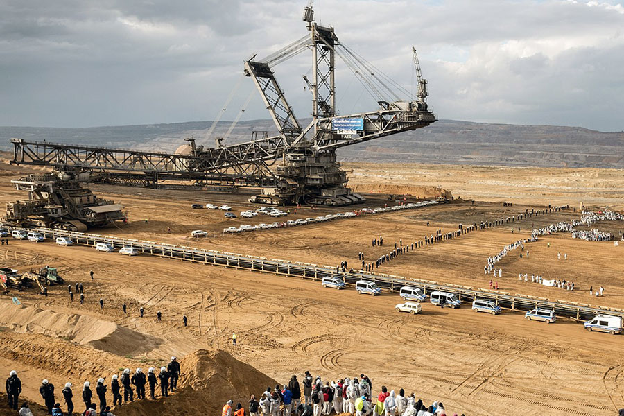 Photo of huge open pit coal mining machine, protestors and police in Germany