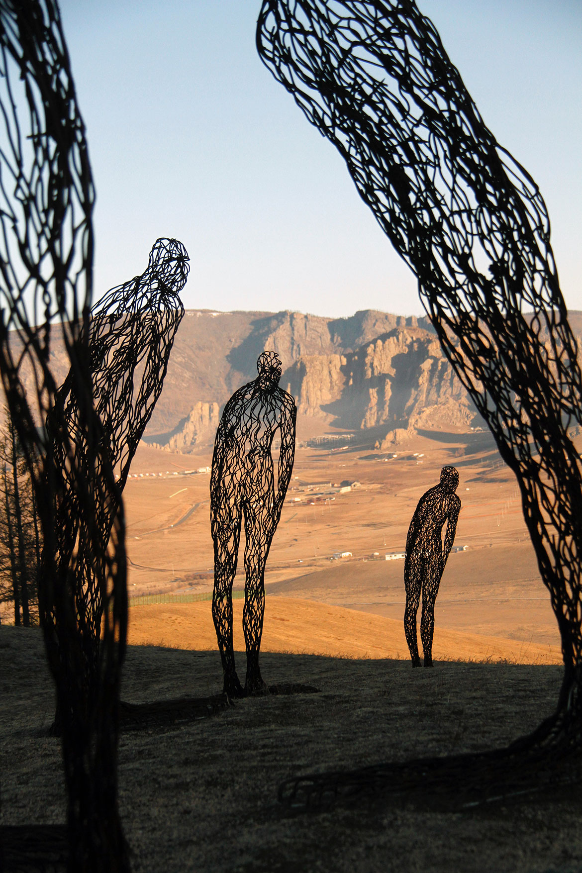 Photo of metal art figures in a dry, sunny landscape with blue sky