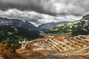 Photo of landscape, Austrian alps with open pit mine, small town and looming mountains